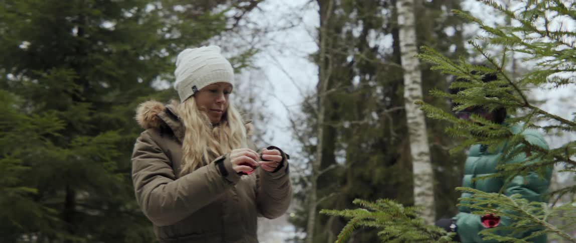 Man and woman decorating Christmas tree outdoors with joyful festive holiday spirit