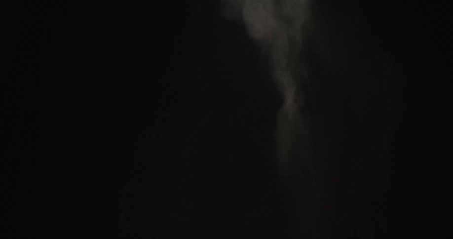 A cloud of smoke appears then dissipates against a black background