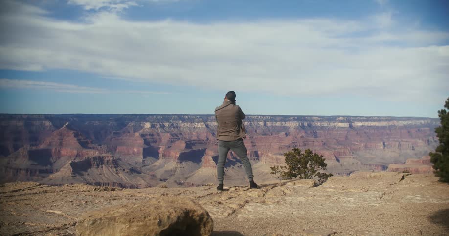 A man with a camera taking photos of the grand canyon