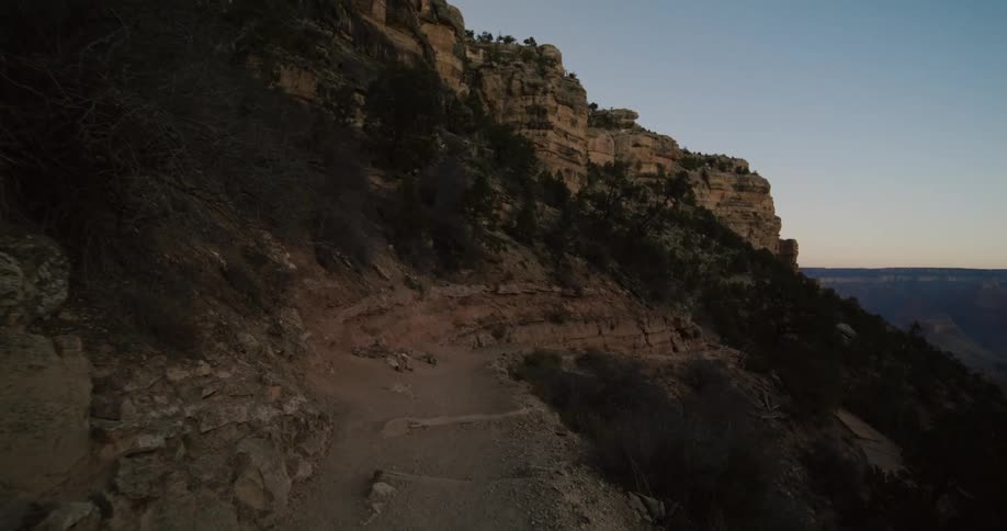 A narrow dirt path along a mountain slope in the evening