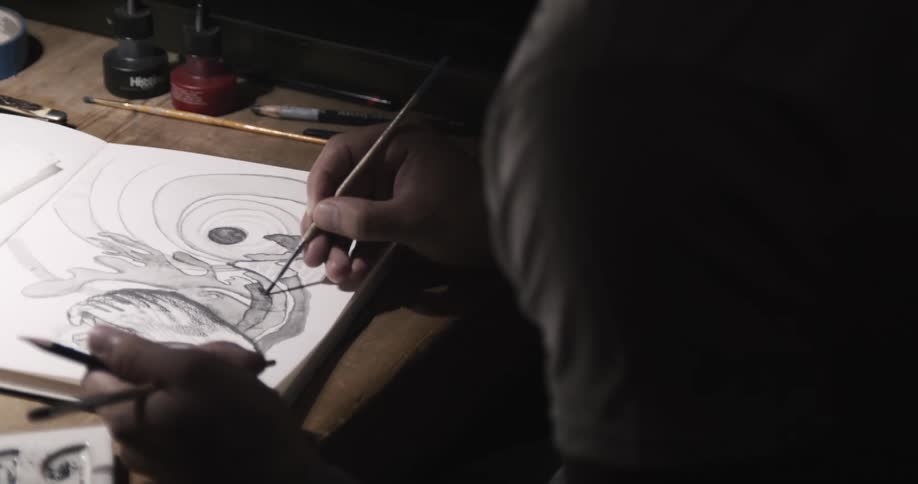 An artist is sitting down painting a picture