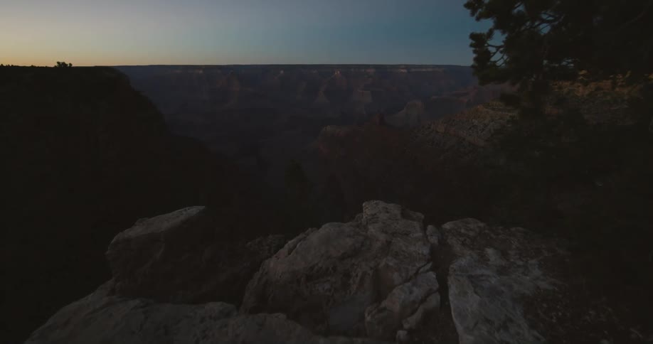 The sun is rising over the edge of a canyon