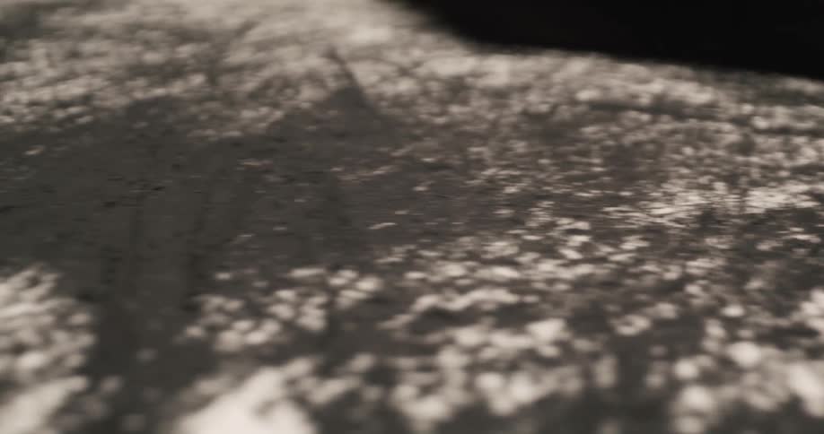 An artist runs their hand along a charcoal drawing