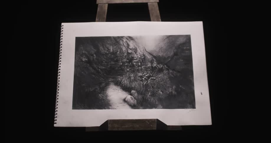 An easel sits in a dark room and a man puts a picture on it and walks away