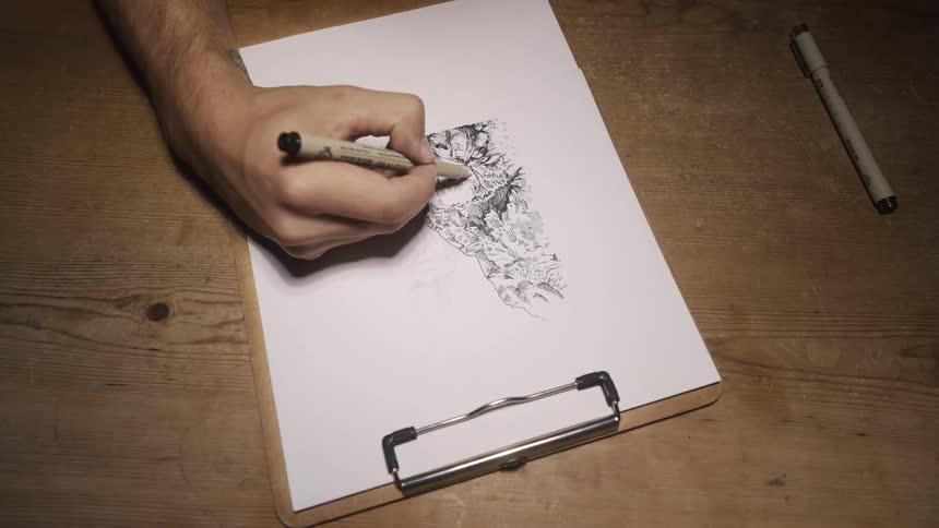 A man uses a pen to draw on a sheet of paper on a clipboard