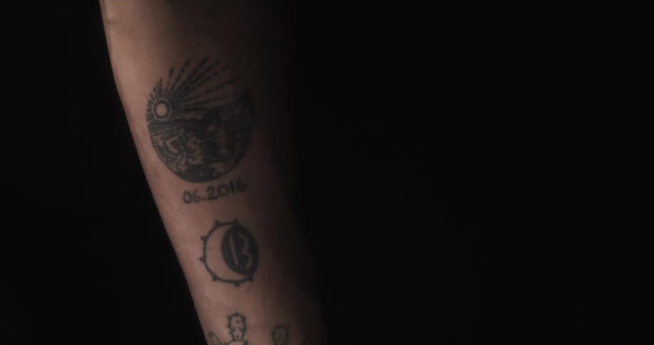 A mans inner forearm is marked with black tattoos