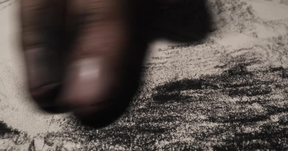 An artist uses a charcoal pencil to draw lines then rubs them into the paper