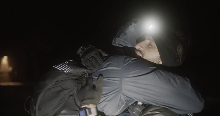 Two men out hiking at night hug one another when they meet up