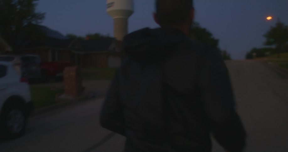 A man runs down the middle of the street in a neighborhood