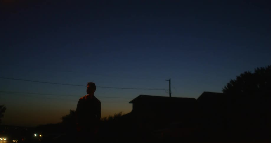 A man stands outside a house at night