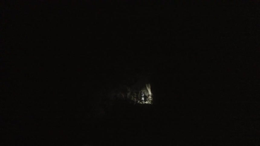 Two men are using a flashlight to see a darkmountain path as they run down