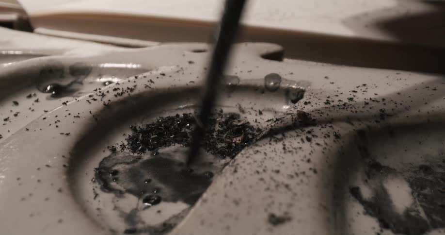 A person mixes the charcoal with a brush