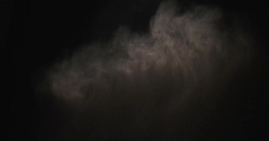 A gray powder bursts in a dark room