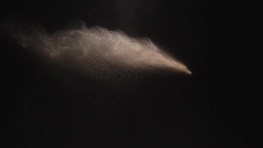 Powder tossed across a black background falls and dissipates