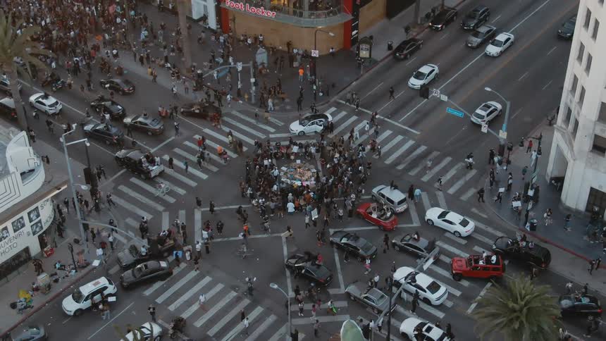 A group of protesters gather in the center of an intersection in a metropolis during the day