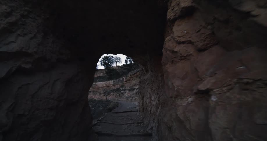 Road passes through tunnel in mountain under a clear sky