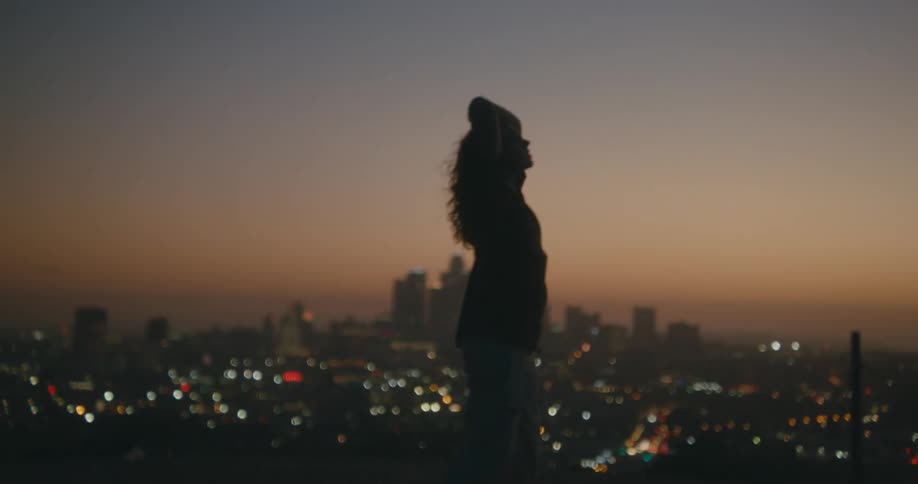 A woman spins around on the hill top
