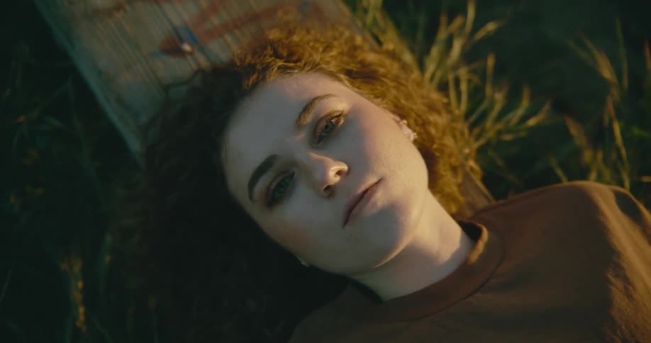 A teenage girl lies outside in the grass