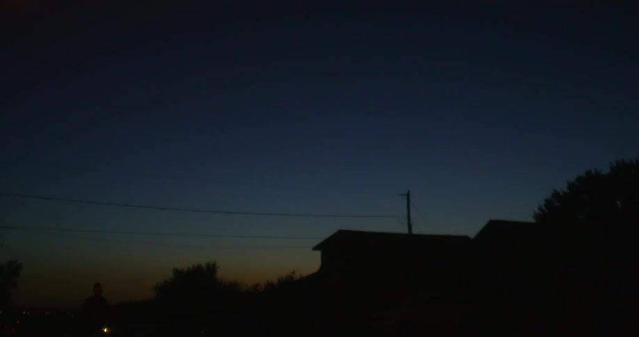 A man jogs through a neighborhood while it is still dark