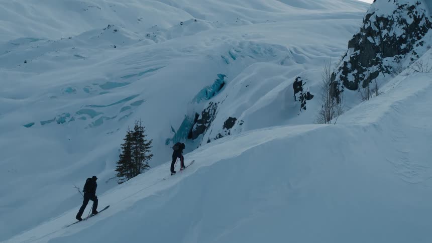A pair of mountaineers climb a snowy mountain slope during the day
