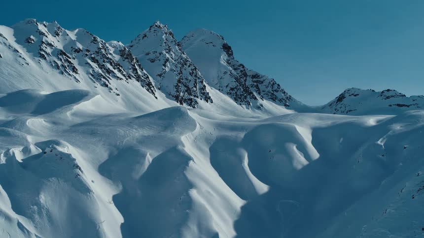 A snow covered mountain ridge with peaks high in a clear sky