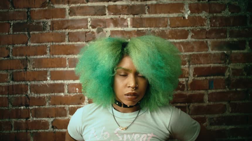 A woman is standing by a brick wall for a portrait