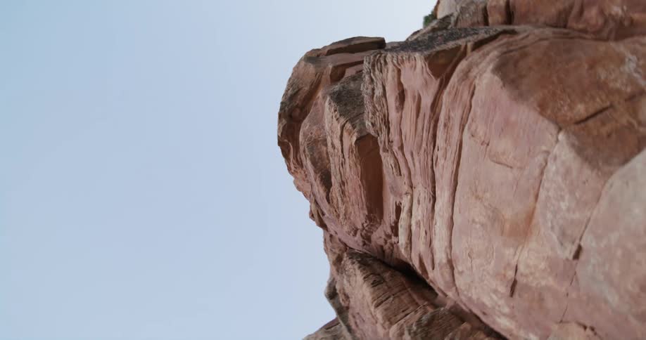 Looking up at a sheer rock cliff face in a canyon against the sky