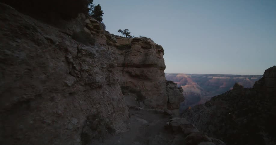 A narrow dirt walkway along the side of a massive canyon during the day