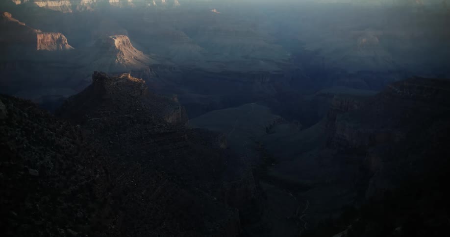 Only tops of some buttes plateaus and mesa catch the sun in wide valley in the badlands