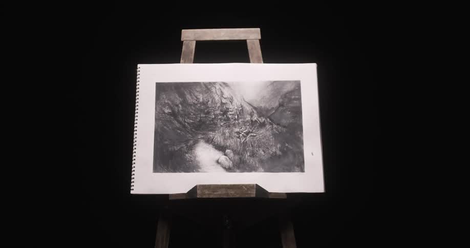 An easel sits in a dark room and a man puts a picture on it and walks away