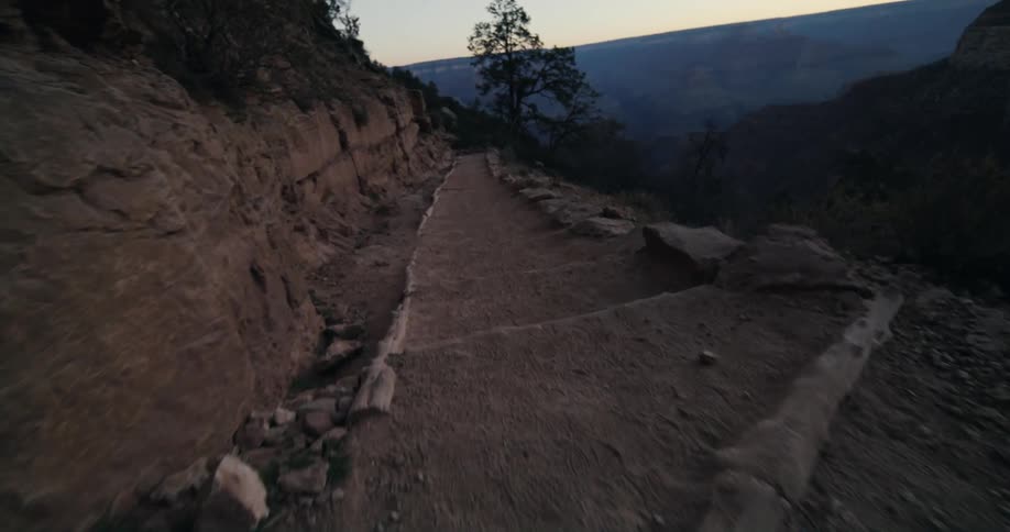 A narrow dirt walkway on the side of a mountain in the evening