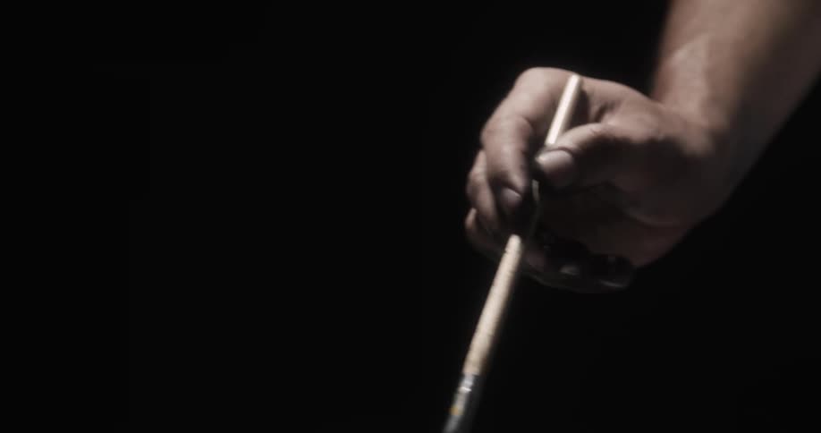 A hand holding and using an art paint brush against a black background