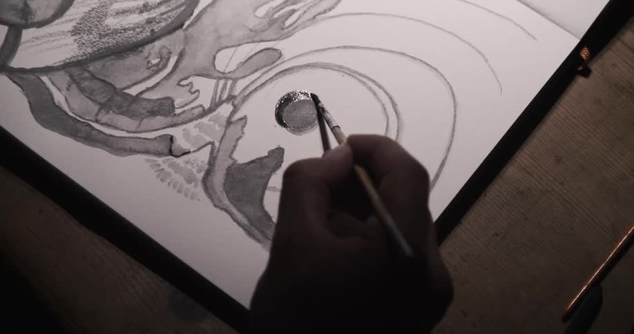 An artist is sitting down painting a picture