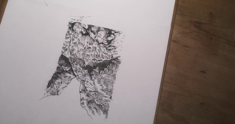 Inked drawing on white paper sits on wooden surface