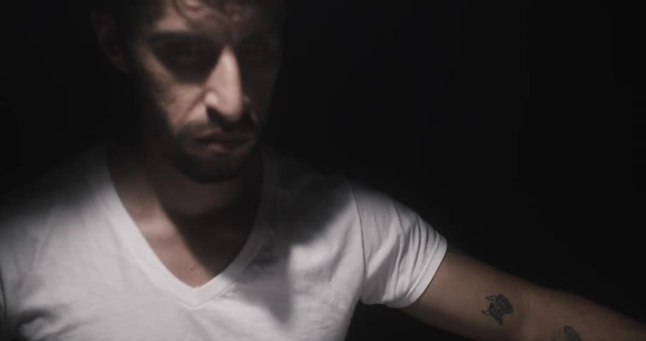 Man moves around in dark room lit by bright light