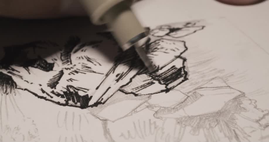 A person sketches on paper with a pen and ink