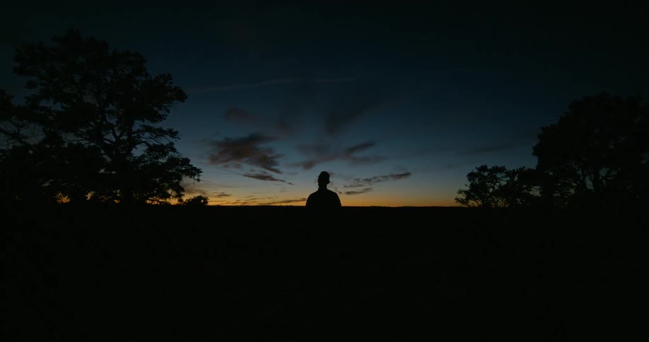 The silhouette of a man outside as the sun sets