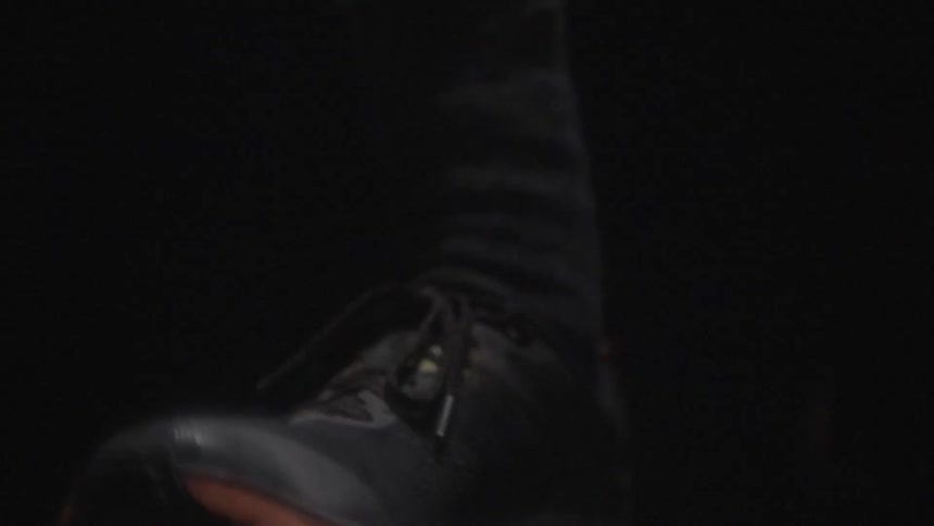 A person wearing sneakers walks through the night