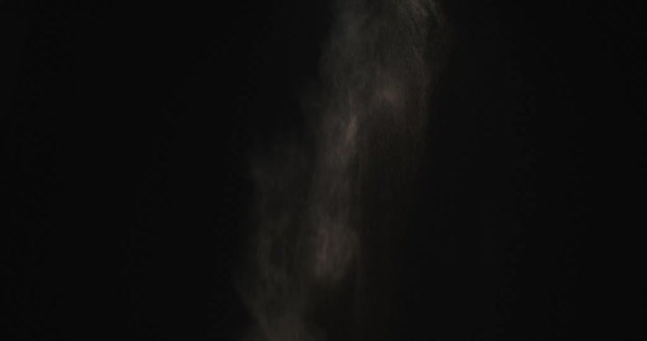 White cloud of particles dissipates against a black background