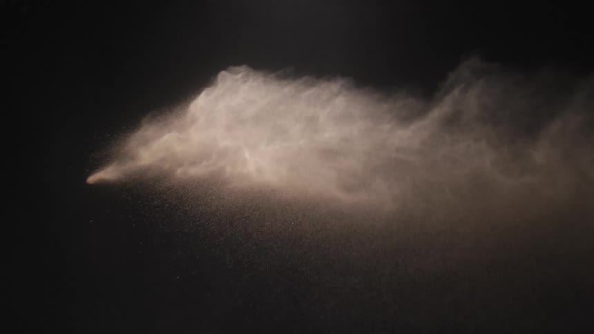 White dust is thrown and spreads through area with dark background