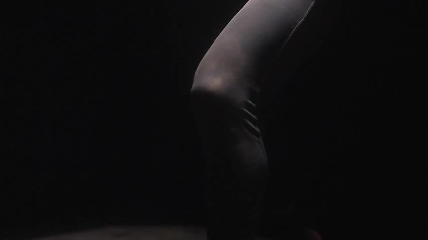 The muscled legs of a person running for exercise against a black background