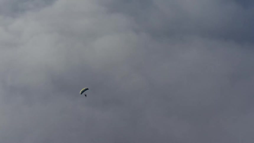 A paraglider is flying high among the clouds