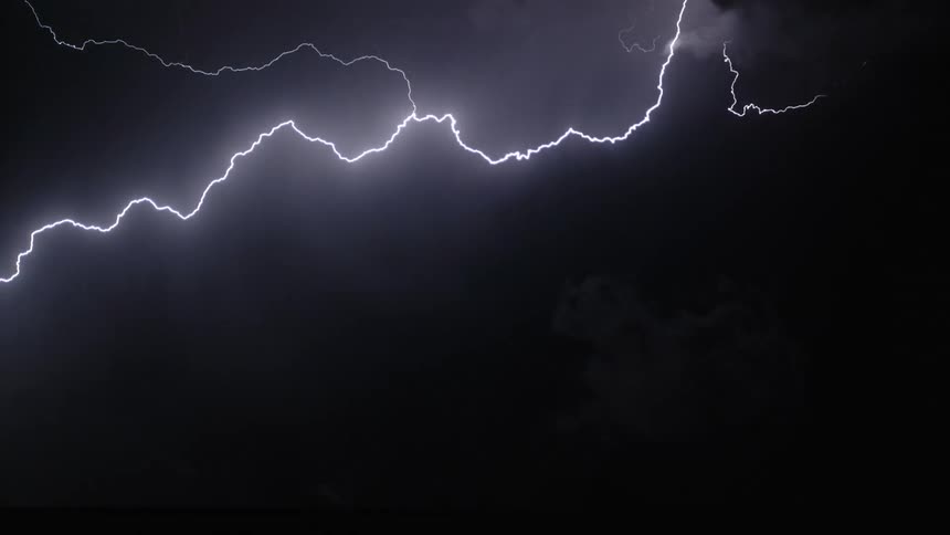 Lightning cracks across a dark sky and flashes brightly