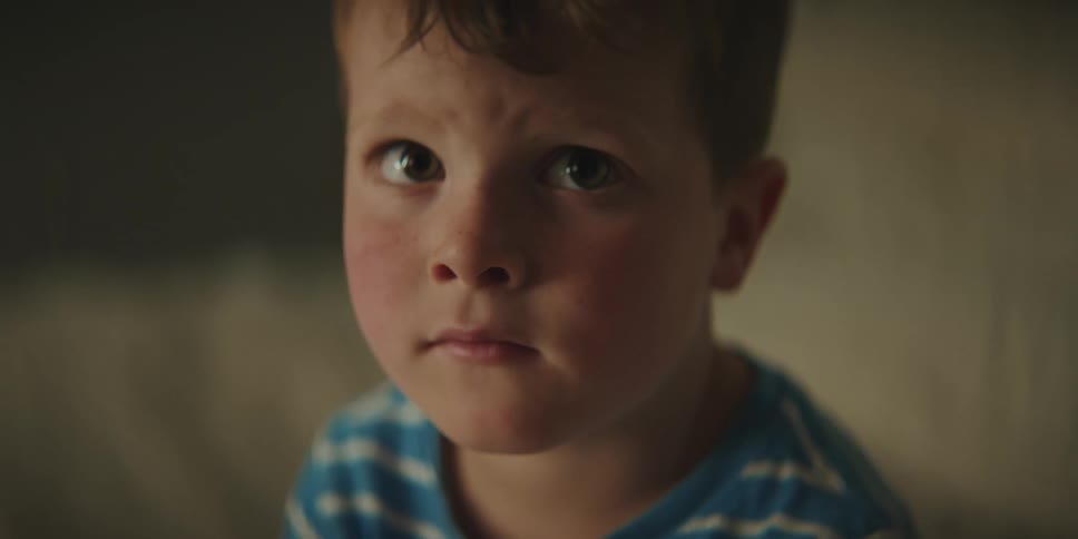 A red faced little boy looks sad