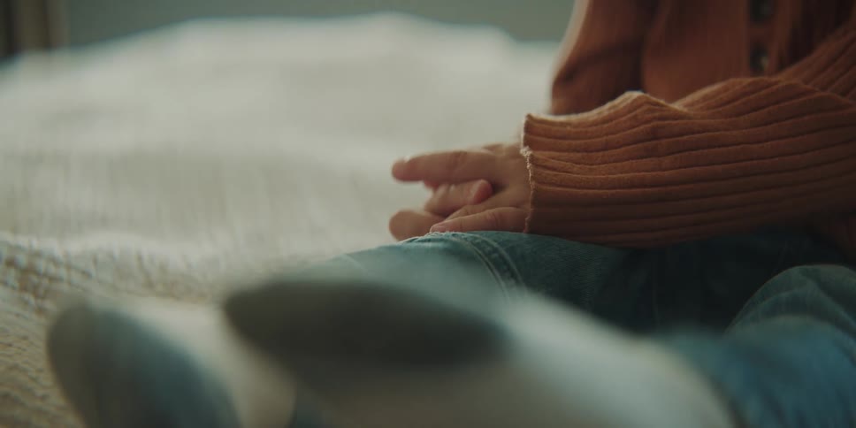 A child is sitting on a blanket on a bed twiddling their fingers