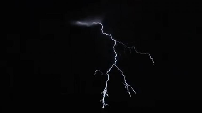 Lightning cracks across a dark sky and flashes brightly