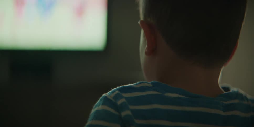 A young boy watches television while sitting indoors