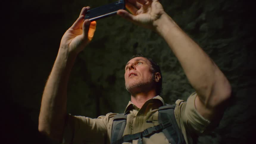 A man uses his smartphone to film the interior of cavern