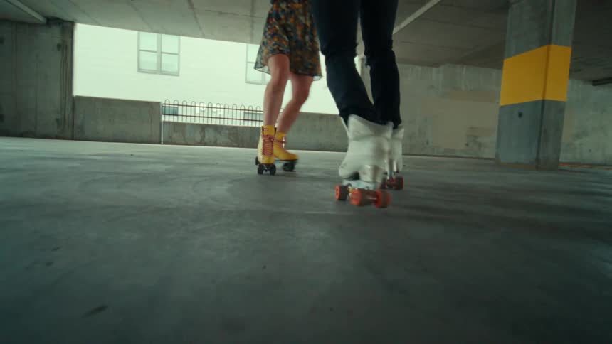 Two people are skating and dancing in a parking garage