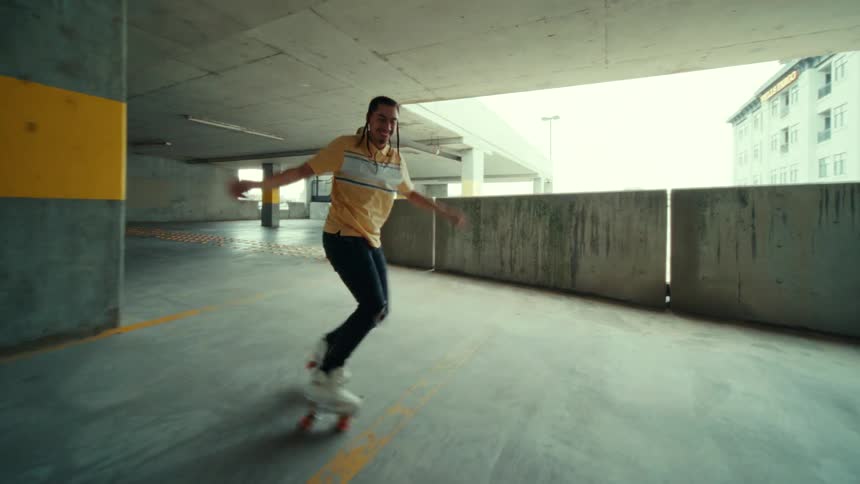 A man dances while wearing roller skates in a parking garage during the day